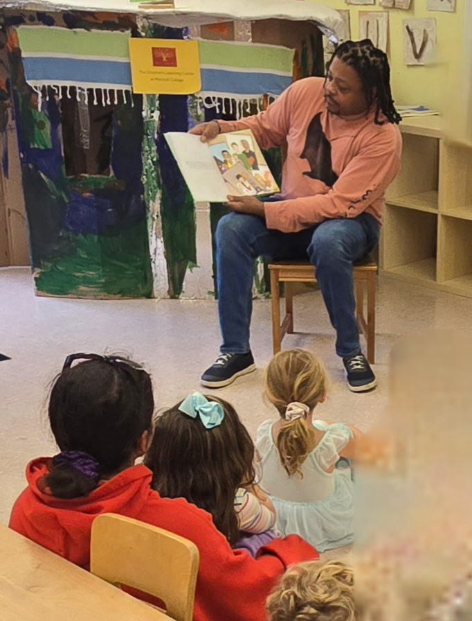 Rod Cornish reading a page of the book to a small group of children